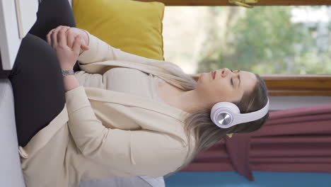 Vertical-video-of-Unhappy-woman-listening-to-music-with-headphones.